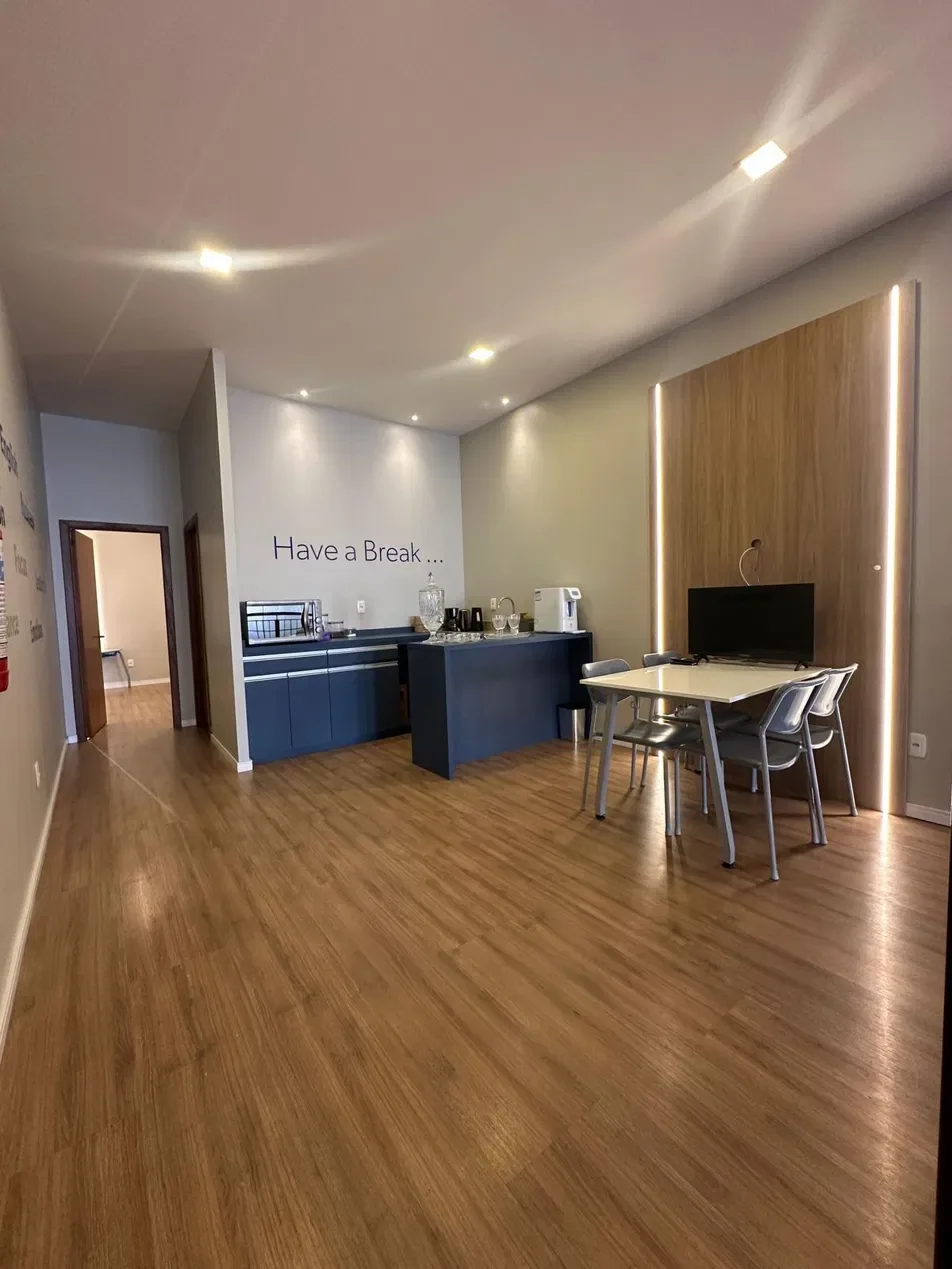 Espaço de convivência da escola com mesa, cadeiras e bancada.