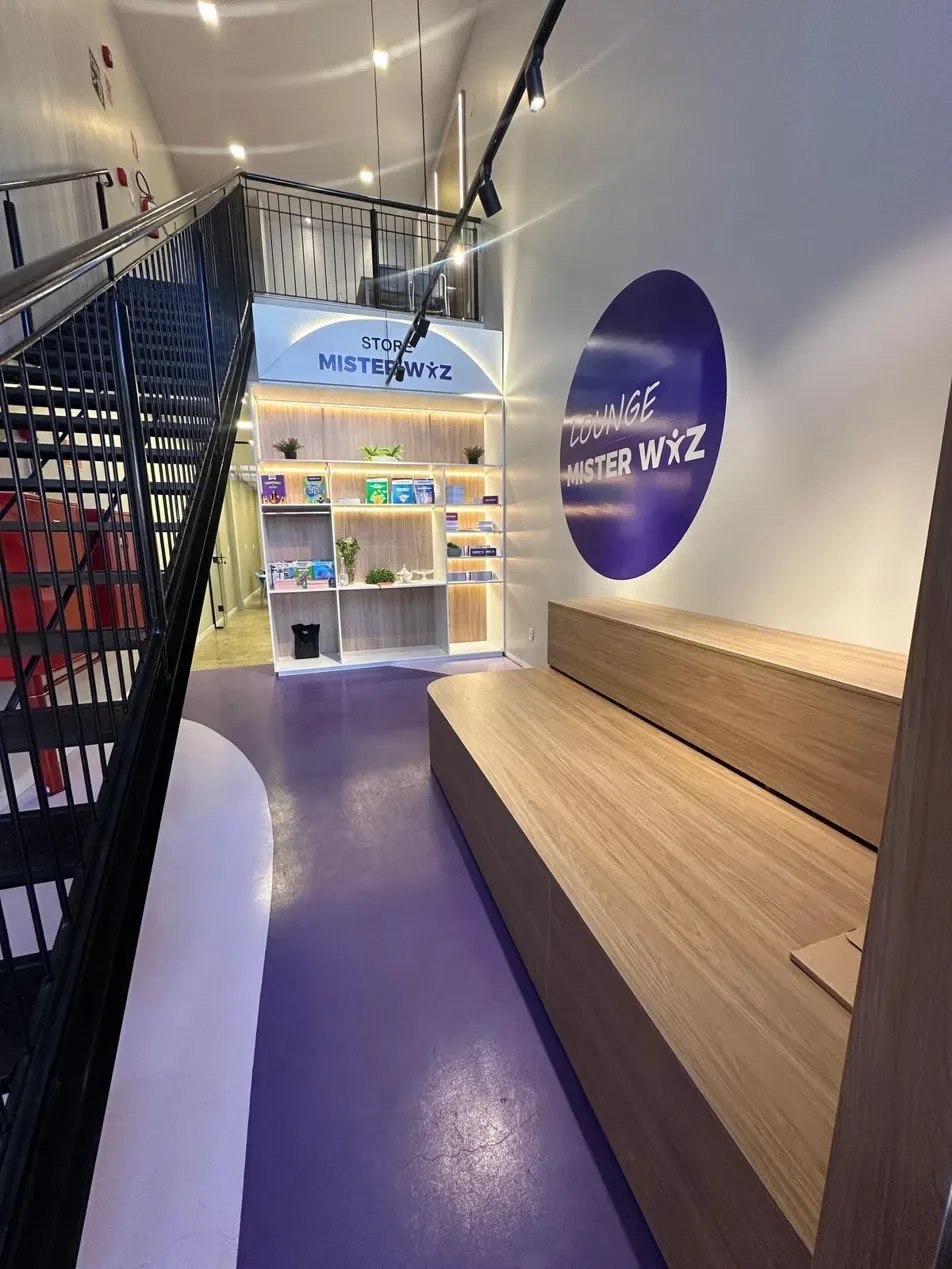 Lounge com banco de madeira e estante de materiais da Mister Wiz.